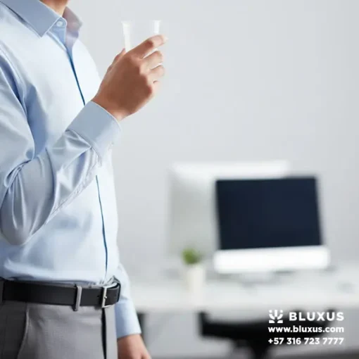Persona sosteniendo copa recolectora estéril para toma de muestra de saliva en entorno laboral.