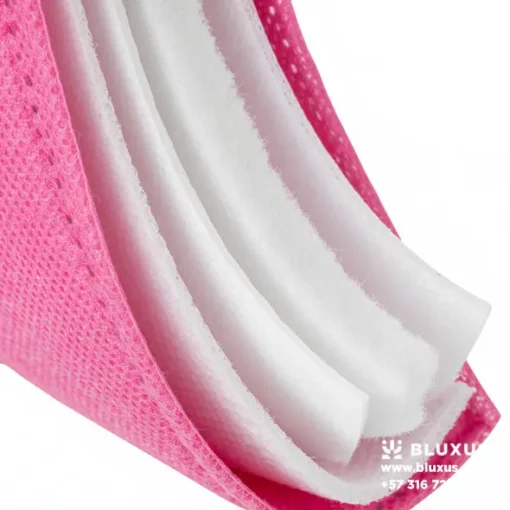Corte transversal de un tapabocas rosado mostrando sus capas internas blancas de filtro Meltblown, garantizando que el color es solo externo y seguro.